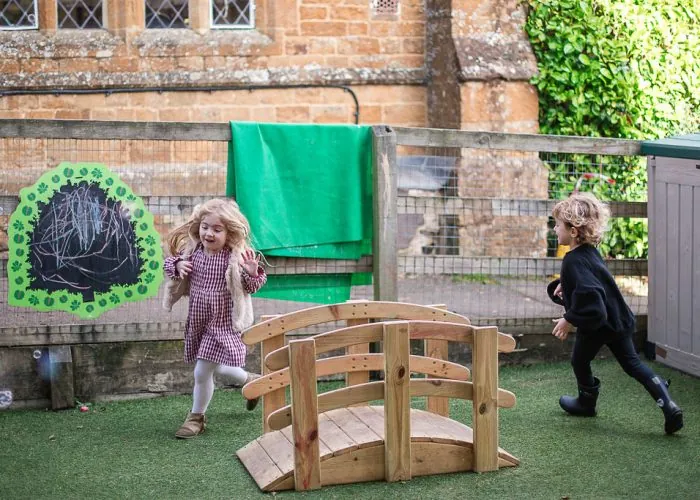 Children playing on a wooden bridge in the outdoor area