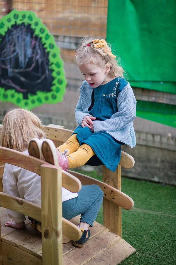 A girl sitting on a wooden bench in the playground