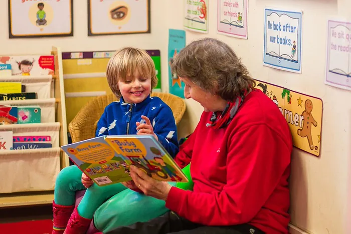 A child reading a book with a member of staff